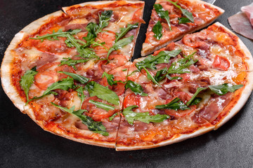 Fresh pizza baked in oven with arugula, salami, cherry tomatoes and mozzarella