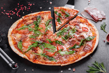 Fresh pizza baked in oven with arugula, salami, cherry tomatoes and mozzarella