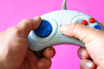 vintage controller for a game console in the hands of a man on a pink background © Максим