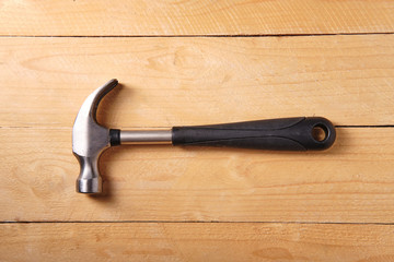 Metal hammer with a black handle on a wooden table