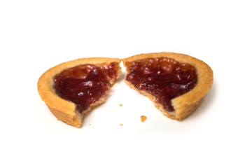 Closeup of crunched mini tartlet with strawberry jam on top view on white background