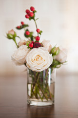 roses and red berries in a glass