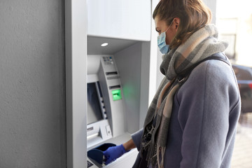 Fototapeta na wymiar finance, bank and hygiene concept - woman in medical mask and glove entreing code at atm machine