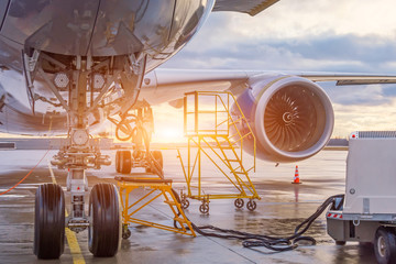 The front landing gear and auxiliary power installation to ensure autonomous power supply of the aircraft, in the background the engine. Evening sunset serviced flight.