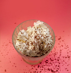 ice-cream with whipped cream and chocolate chips on a pink backg