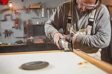 Male carpenter working on old wood in a retro vintage workshop.