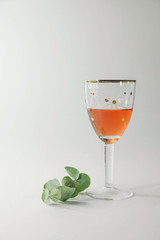  Vintage wine glass with rose wine and a branch of eucalyptus on a white background. Vertical image. Copy space.