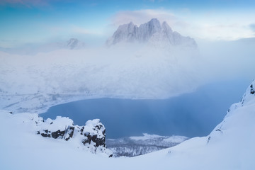Fototapeta na wymiar Pink early morning glow light on snow covered mountains in arctic norway, super wide panoramic scene. Scenic winter view of snowy mountain in Scandinavia. Beautiful landscape concept background.