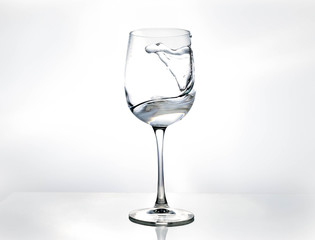 Water in a wine glass. Splash of liquid on a white background. Isolated object. Spray. Selective focus.