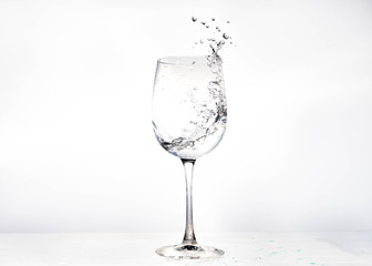 Water in a wine glass. Splash of liquid on a white background. Isolated object. Spray. Selective focus.