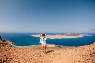 Fototapeta na wymiar Viewpoint to La Graciosa from Lanzarote and happy traveller woman. View of La Graciosa Island and blue ocean