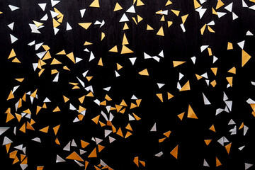 Golden silver confetti isolated on black background.