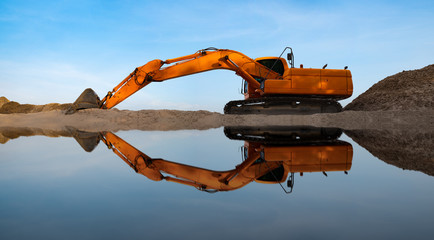 Excavators are digging the sand in the riverside on the blue sky background - obrazy, fototapety, plakaty