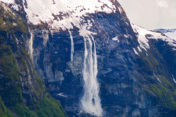 Avalanche of snow cascading down steep mountain or cliff in Geirangerfjord in Norway with snow...
