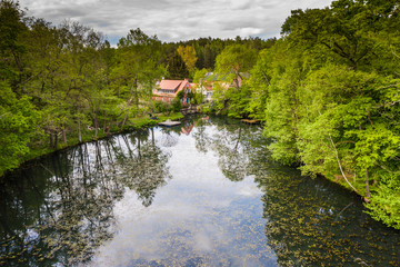 idyllic house near a forest lake nestled in a deciduous forest in spring - aerial view