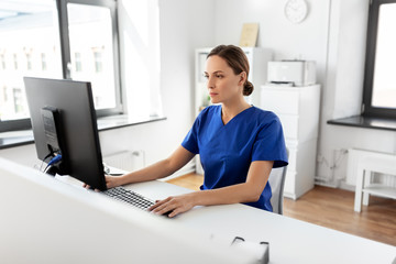 medicine, technology and healthcare concept - female doctor or nurse with computer working at...