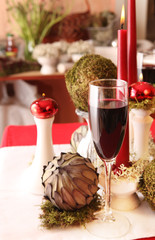 table decoration in white, green and red scheme with candles, moss, artichokes, glasses of wine
