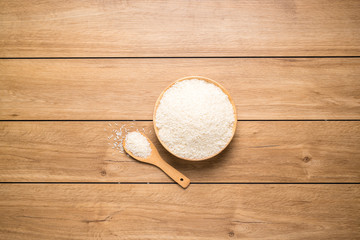 A pile of grains in a wooden bowl and a wooden spoon resting on a wooden table, with copy space, top view.