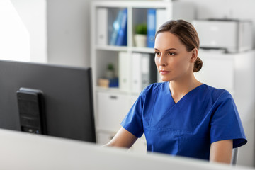 medicine, technology and healthcare concept - female doctor or nurse with computer working at...