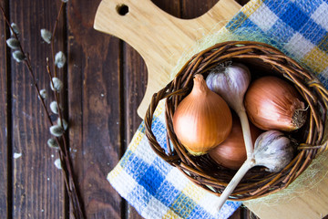 Chicken eggs. Brown chicken eggs in basket on the cutting board on wooden background, close up. Still life with eggs, garlic, onion. Farm natural products. Egg and vegetables is ingredient for cooking