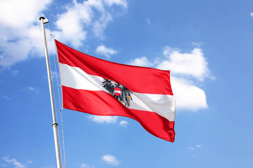 Austrian national flag swings under blue sky