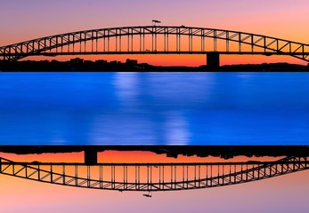 Naklejka premium Mirrored view of Sydney Harbour with all the vibrant colours on a orange and blue sunset afternoon 