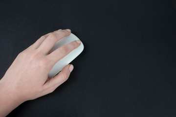 Caucasian left-handed woman using computer mouse. Female hand holding computer mouse on dark black...