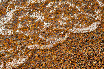 Sand and wave in the surf close up