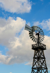 Old fashion metal windmill and blue sky with clouds in the distance landscape