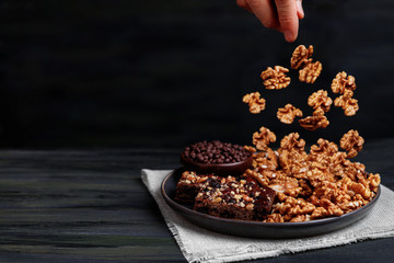 walnuts falling from above onto pieces of chocolate brownie and walnuts close-up
