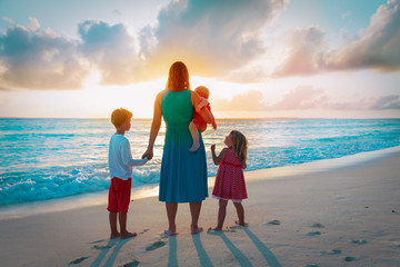 mother and kids walking on beach at sunset