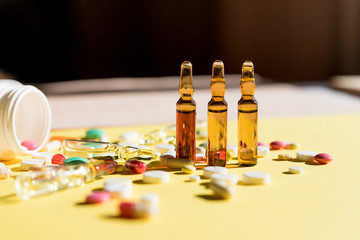 medical ampules, bottle, pills isolated on yellow background.Selective focus.Ampoules for injections.Medical background.coronavirus epidemic.medicine and pharmacy drugs