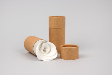 Paper tubes with white cotton disks inside on grey background with copyspace. Reusable packaging and recycling concept showing how to reuse cardboard packaging at home. Mockup