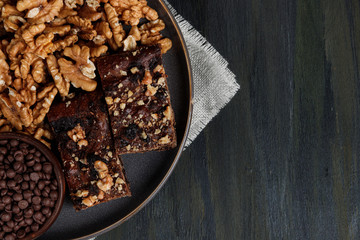 chocolate and walnut brownie next to walnuts and chocolate