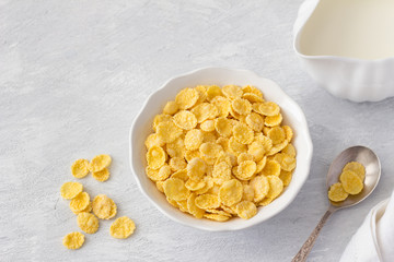 Sweet crunchy cornflakes with milk on a gray textured background. Fast tasty breakfast, top view, free space, horizontal