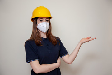 The Worker woman with helmet wears a protective antivirus mask such as coronavirus covid-19 or sars