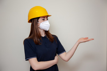 The Worker woman with helmet wears a protective antivirus mask such as coronavirus covid-19 or sars