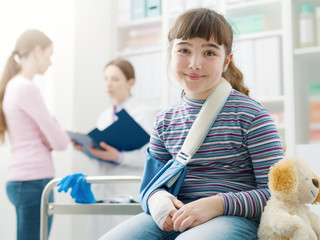 Cute smiling girl with arm brace and teddy bear