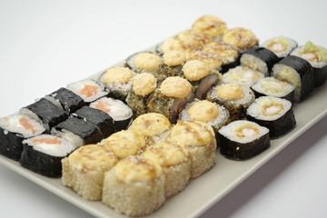 Many different sushi rolls on a plate on an isolated background.
