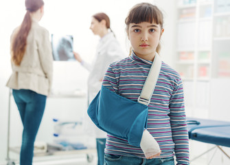 Cute girl with arm brace in the doctor's office