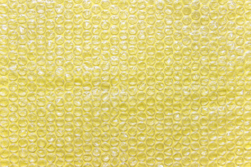 Yellow bubble wrap air filled transparent packaging foil placed on yellow backgound.