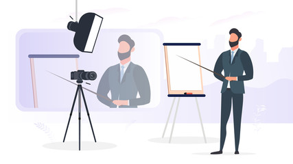 A man in a business suit with a tie is giving a presentation to the camera. The teacher is writing a lesson. The concept of blogging, online training and conferences. Camera on a tripod, softbox. 