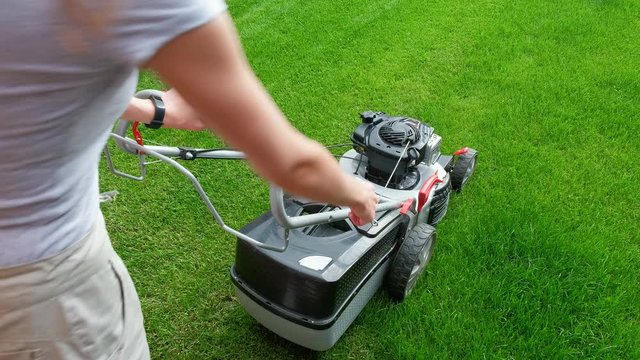 Woman trying to start a lawn mower. without start.View from behind the shoulder