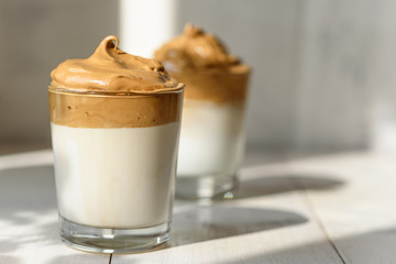 trendy dalgona coffee in glass on white background with shadow, korean coffee concept