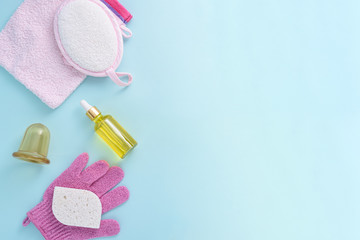 shower accessories, washcloth, sponge, serum, oil, vacuum massager on blue background, Spa day, self-care, wellness, copy space