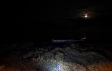 Night scene on the beach. Illuminated in the foreground. And a lunar path in the sea reflected from the moon. Top view.  Pomorie resort, Bulgaria.