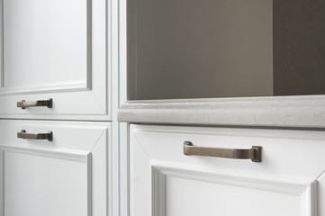 the end of a stone countertop in a classic kitchen with painted white facades