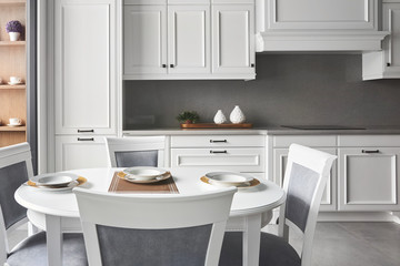 Italian kitchen in classic style with white painted facades with a dining table for 4 people