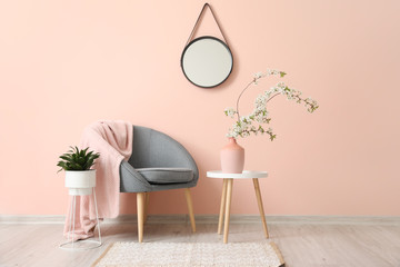 Interior of living room with stylish mirror and blooming tree branches