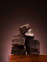 Closeup pieces dark chocolate on wooden board